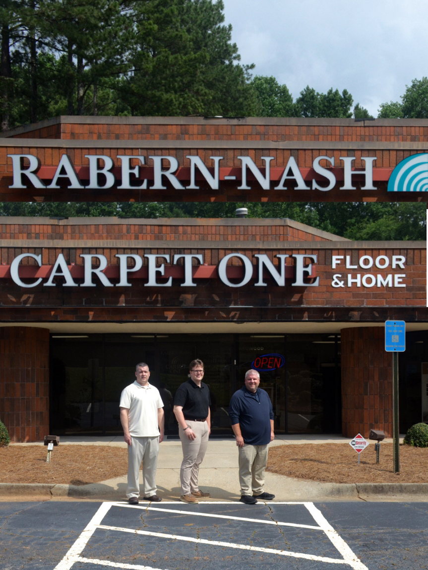 RABERN-NASH CARPET ONE FLOOR & HOME owners of in front of the storefront.